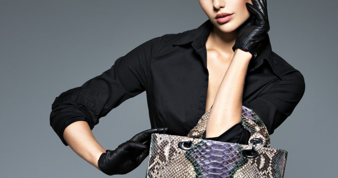 Beautiful woman in black holds fashion handbag