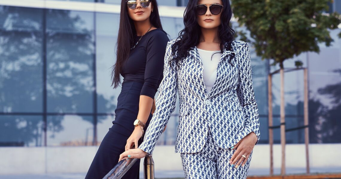 Two business women dressed in a stylish formal clothes, standing outdoors